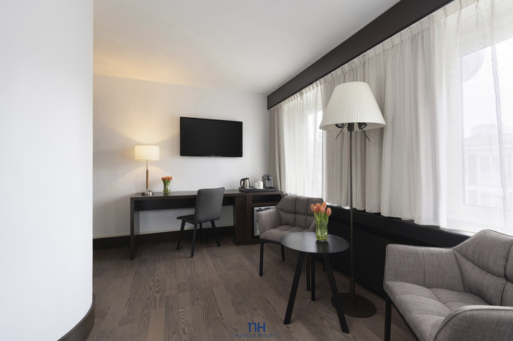 Ein modernes Hotelzimmer mit Schreibtisch, Fernseher und Sesseln.