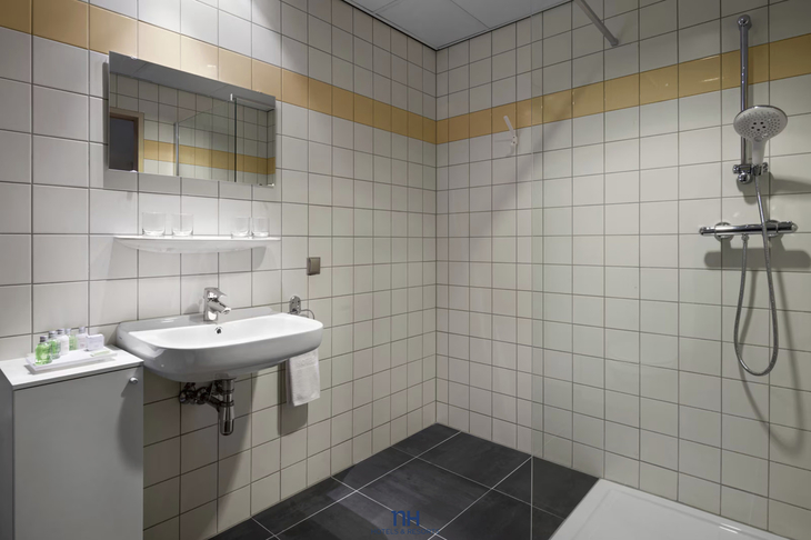 Badezimmer mit Dusche, Waschbecken, Spiegel und Fliesenwänden.