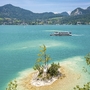 Schiff auf dem Wolfgangsee, umgeben von Bergen und kleiner Insel im Vordergrund.