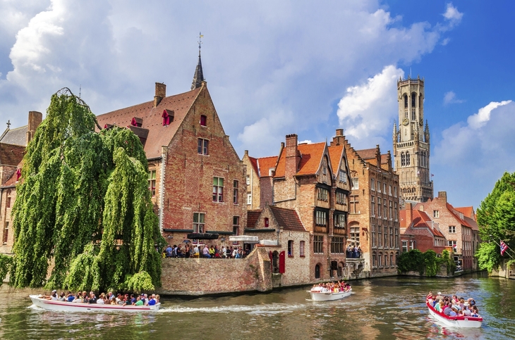 Kanal in der Altstadt von Brügge mit historischen Gebäuden und vorbeifahrenden Booten.