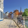 Fahrrad lehnt an einem Geländer entlang eines Kanals in Brügge bei sonnigem Wetter.