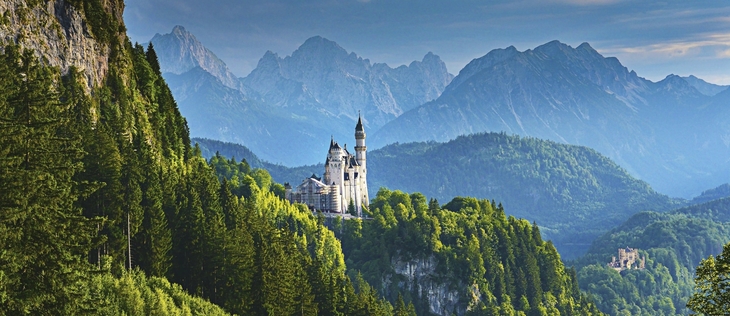 Schloss Neuschwanstein in Bayern, umgeben von grünen Wäldern und Bergen.