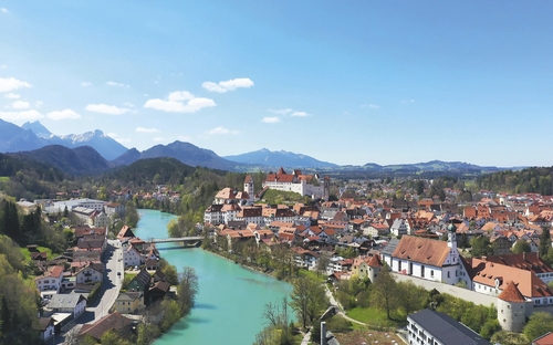 Luftaufnahme von Füssen im Allgäu mit Lech und Bergen im Hintergrund.
