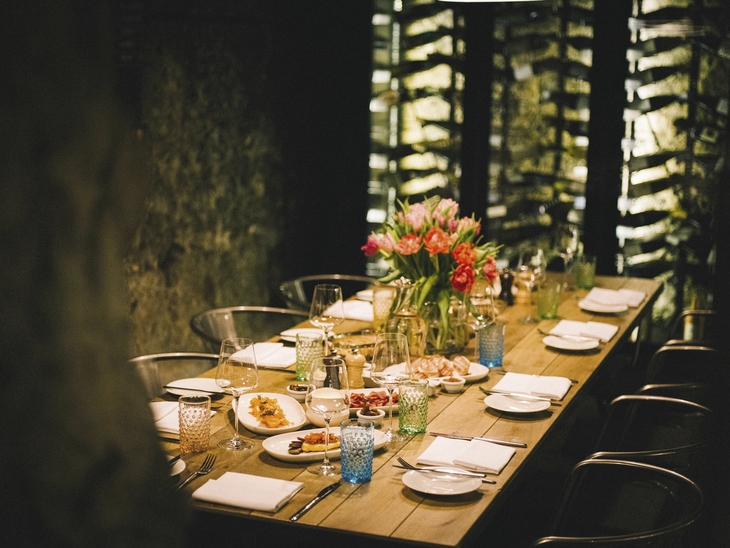 Eleganter gedeckter Tisch in einem stimmungsvoll beleuchteten Raum mit Blumenarrangement.