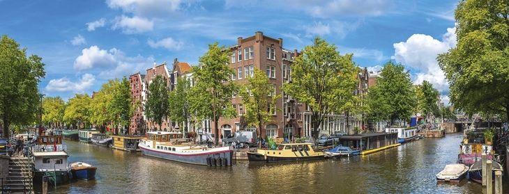Kanal und historische Gebäude in Amsterdam bei Sonnenschein.