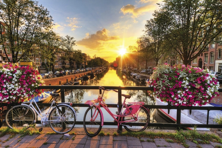 Fahrräder auf Brücke über Kanal in Amsterdam bei Sonnenuntergang.