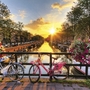 Fahrräder auf Brücke über Kanal in Amsterdam bei Sonnenuntergang.