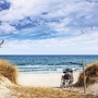 Fahrrad am Nordseestrand mit Dünen unter blauem Himmel.