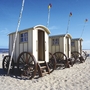 Drei historische Badewagen am Strand von Norderney bei sonnigem Wetter.