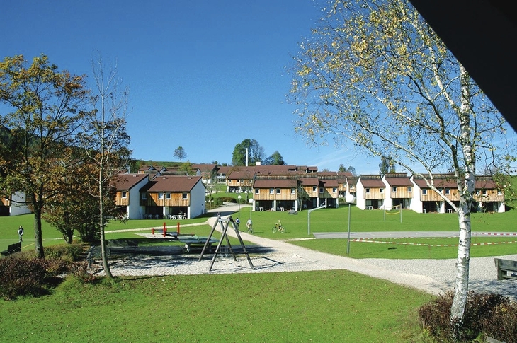 Wohnsiedlung mit Spielplatz und Bäumen vor blauem Himmel in Inzell.