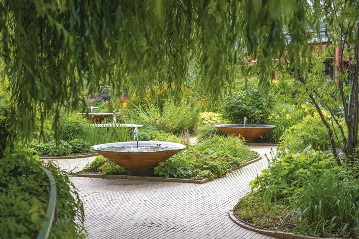 Gartenweg mit Springbrunnen und üppiger Vegetation im Tivoli in Kopenhagen.