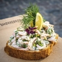 Smørrebrød mit Krabben, Dill und Zitrone auf einem hölzernen Untergrund.