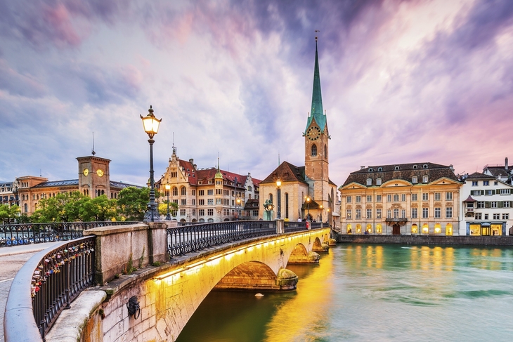 Brücke und historische Gebäude in Zürichs Altstadt bei Sonnenuntergang.