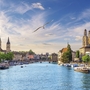 Fluss in Zürich mit historischen Gebäuden und blauen Himmel.