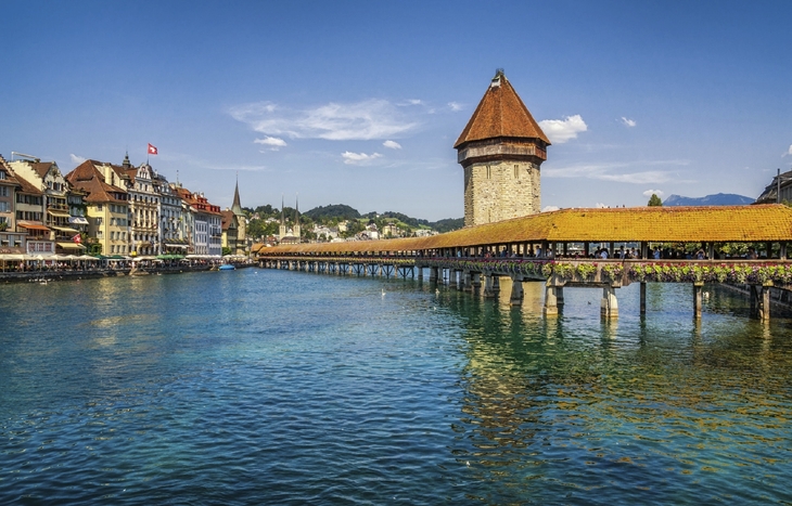 Kapellbrücke in Luzern über dem Wasser mit Turm und Altstadt im Hintergrund.