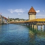 Kapellbrücke in Luzern über dem Wasser mit Turm und Altstadt im Hintergrund.
