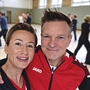Trainerpaar in Turnhalle mit Menschen im Hintergrund beim Training