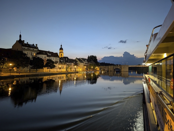 Bootsfahrt bei Sonnenuntergang in Kitzingen mit Blick auf Fluss und Uferhäuser.