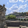 Statue auf einer Brücke mit Festung Marienberg im Hintergrund in Würzburg.