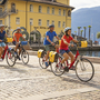 Gruppe von Radfahrern in der Stadt am Seeufer bei sonnigem Wetter.