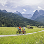 Radfahrerpaar genießt Berglandschaft bei sonnigem Wetter auf einem Fahrradweg.