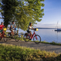 Radfahrer am Starnberger See nahe einem Bootshafen im Sonnenuntergang.