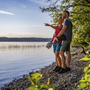Paar macht Radpause am Starnberger Seeufer, schaut auf das Wasser bei sonnigem Wetter.