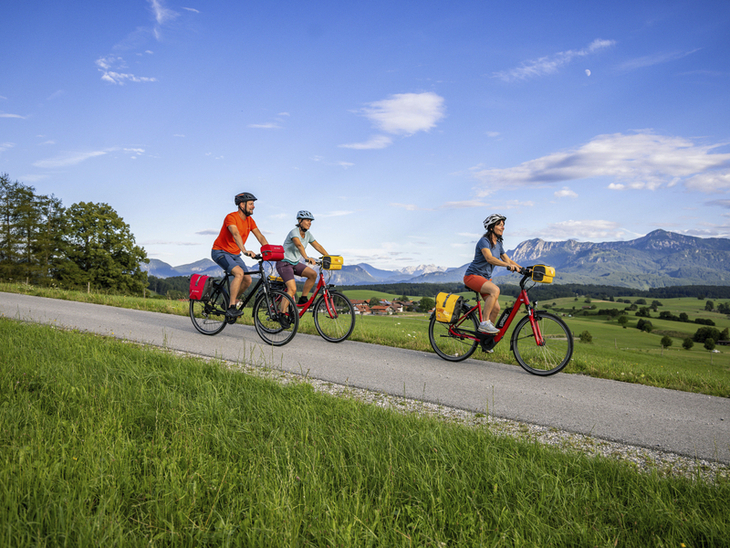 Radfahrer auf einer ländlichen Straße mit Berge im Hintergrund.