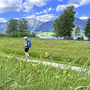 Wanderer spaziert am Seeuferweg im Salzkammergut mit Bergen im Hintergrund.