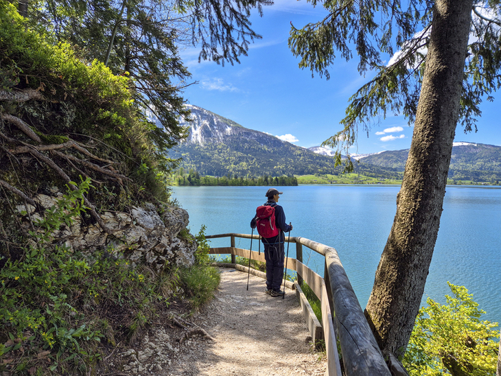 Wanderer mit Rucksack auf Weg am Wolfgangsee, Berge im Hintergrund