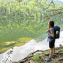 Wanderer blickt auf den Nussensee, umgeben von Wald und ruhigem Wasser.