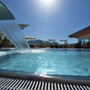 Pool des Gartenhotel Pfeffel Dürnstein bei sonnigem Wetter, mit Wasserfall und Liegestühlen.