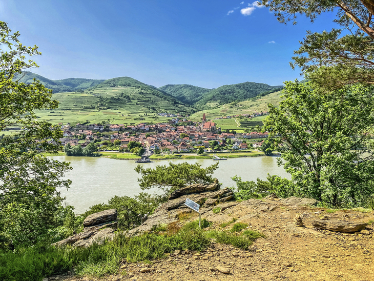 Blick auf Rossatz mit Donau und umliegenden Hügeln in der Wachau bei klarem Wetter.