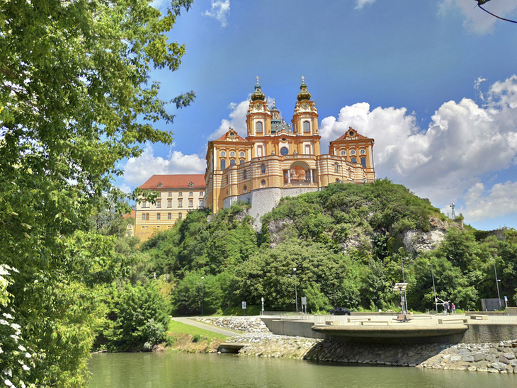 Kloster Stift Melk auf einem Hügel, umgeben von grüner Landschaft und klarem Himmel.