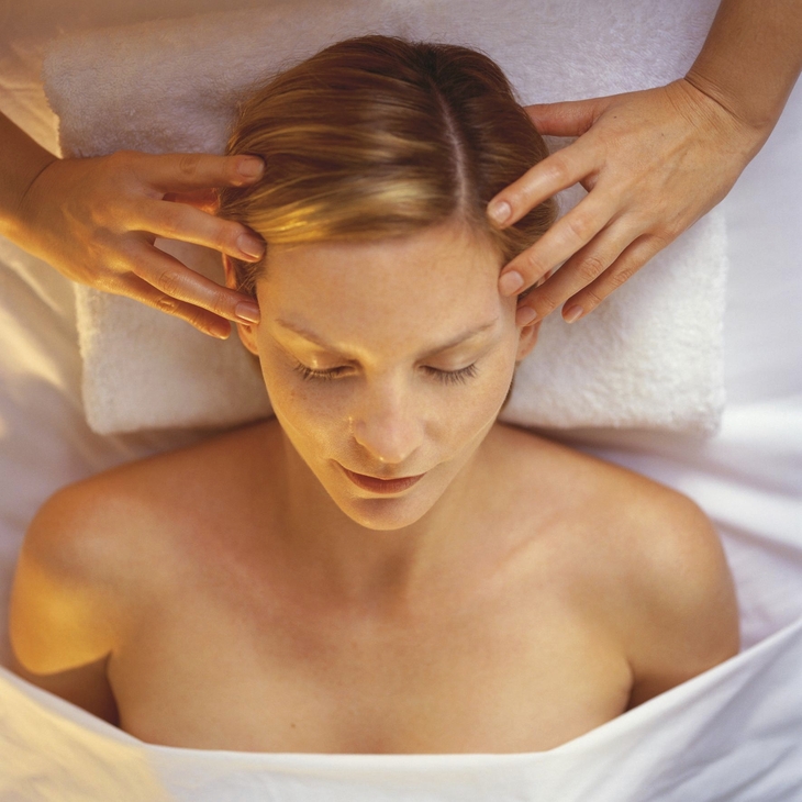 Person erhält eine Kopfmassage auf einem weißen Handtuch.