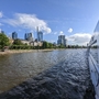 Blick vom Fluss auf Frankfurts Skyline mit Wolkenkratzern bei sonnigem Wetter.
