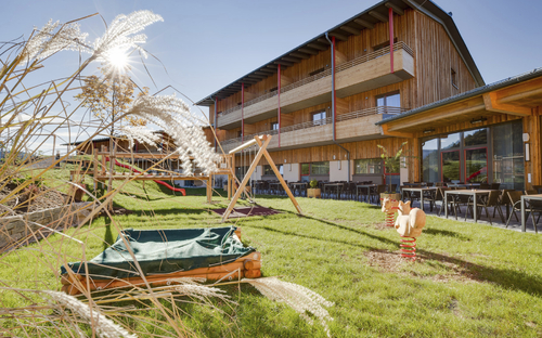 Hotelansicht mit Spielplatz und Terrasse im Sommer, JUFA Hotel Annaberg.